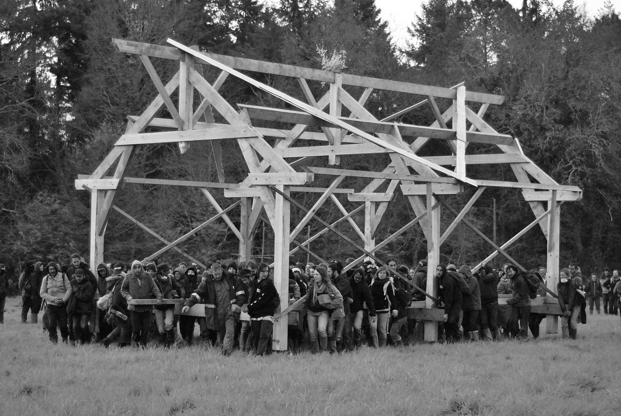 People carry a new assembly hall made from local trees to replace the one destroyed by the police